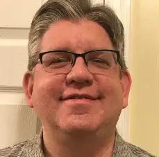 Man wearing glasses smiling indoors.